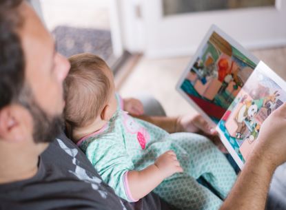 Man reading to baby on his lap